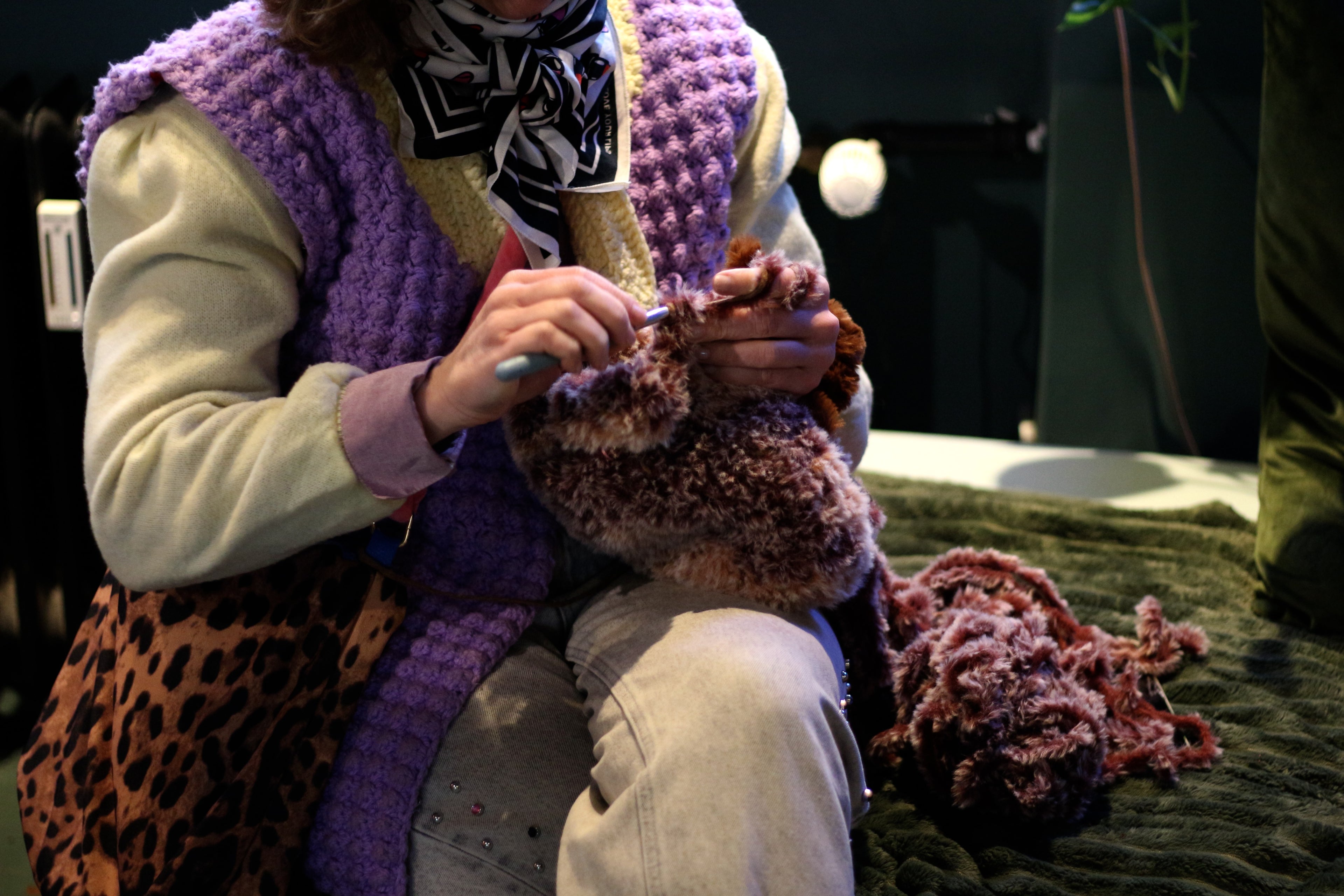 a woman hand crocheting a furry bag