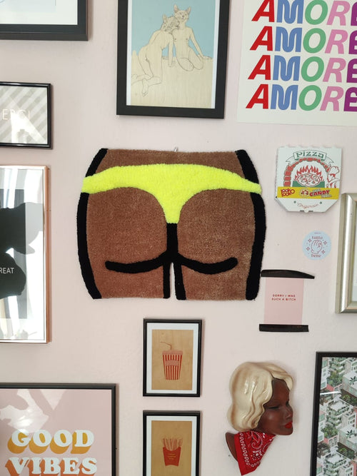 a wall rug / tapestry representing booty in yellow thong, wall decorations around