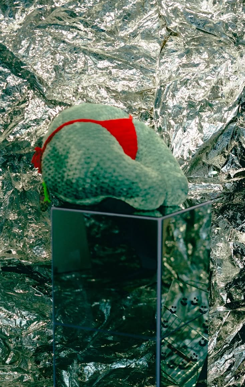 aluminium background with mirror display, chunky yarn booty pillow on it with red tanga