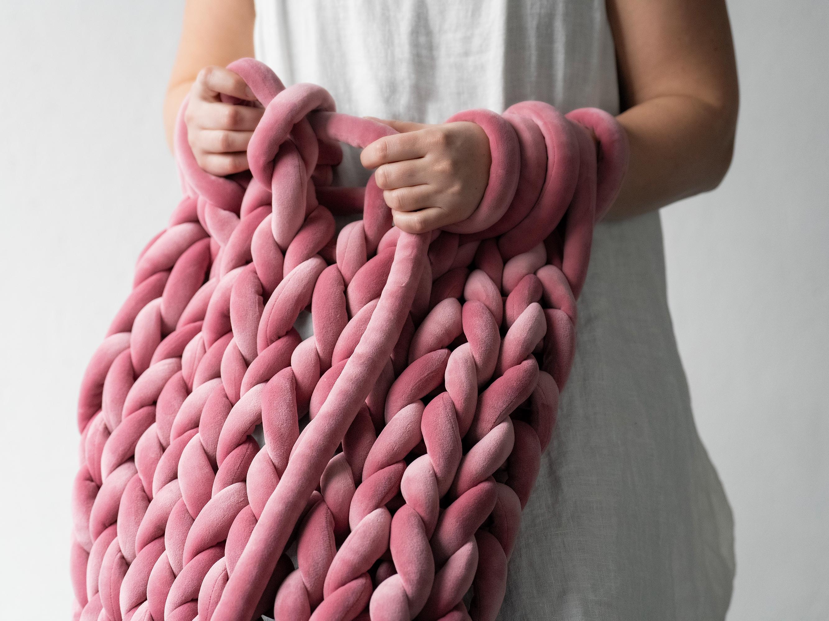a woman crocheting / pink chunky yarn